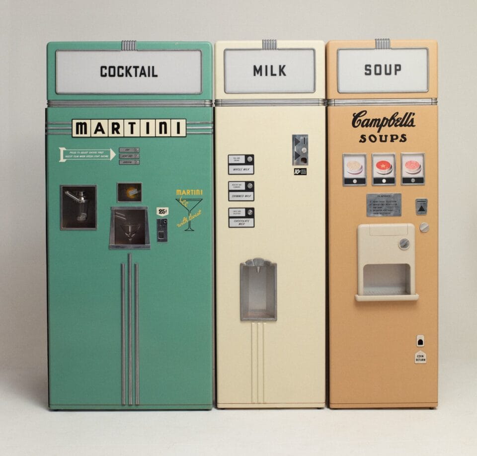 a set of three vending machines labeled "cockails," "milk," and "soup"