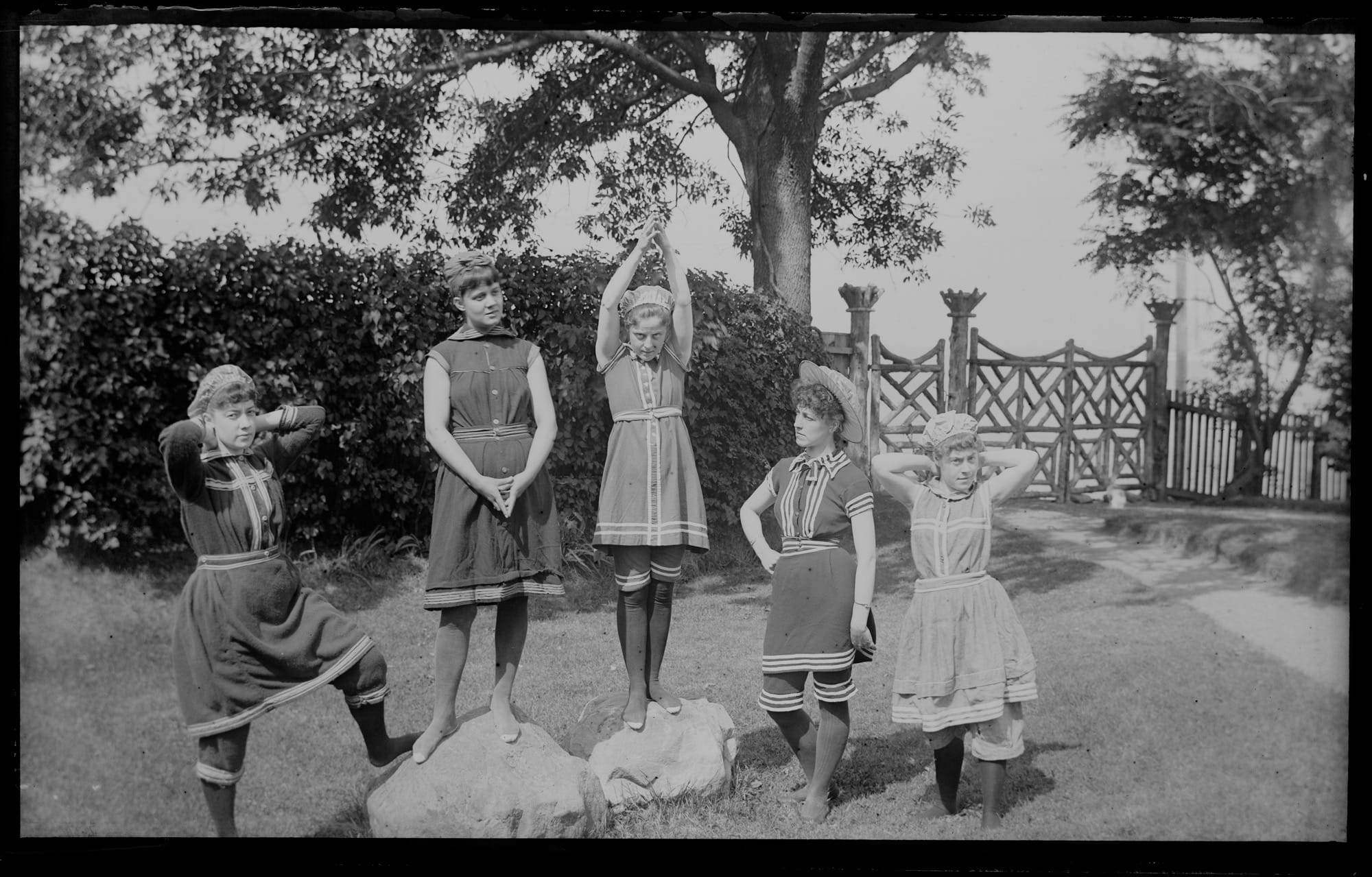 a black-and-white photo from the late 19th century of young people in swimming outfits, making funny poses