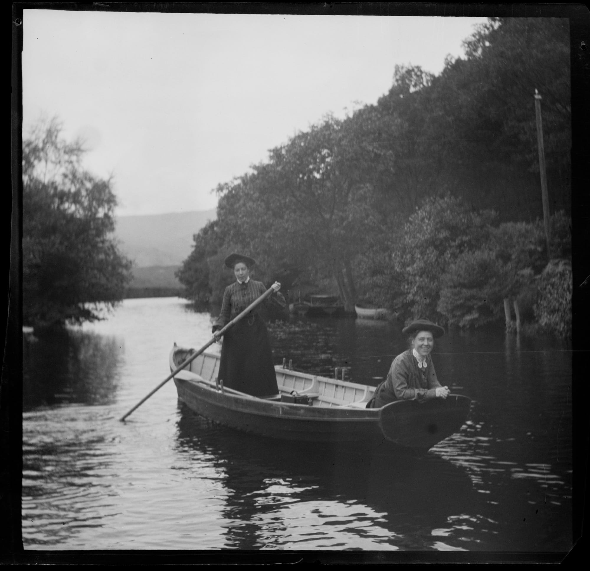 a black-and-white photo from the late 19th century of two women in a rowboat