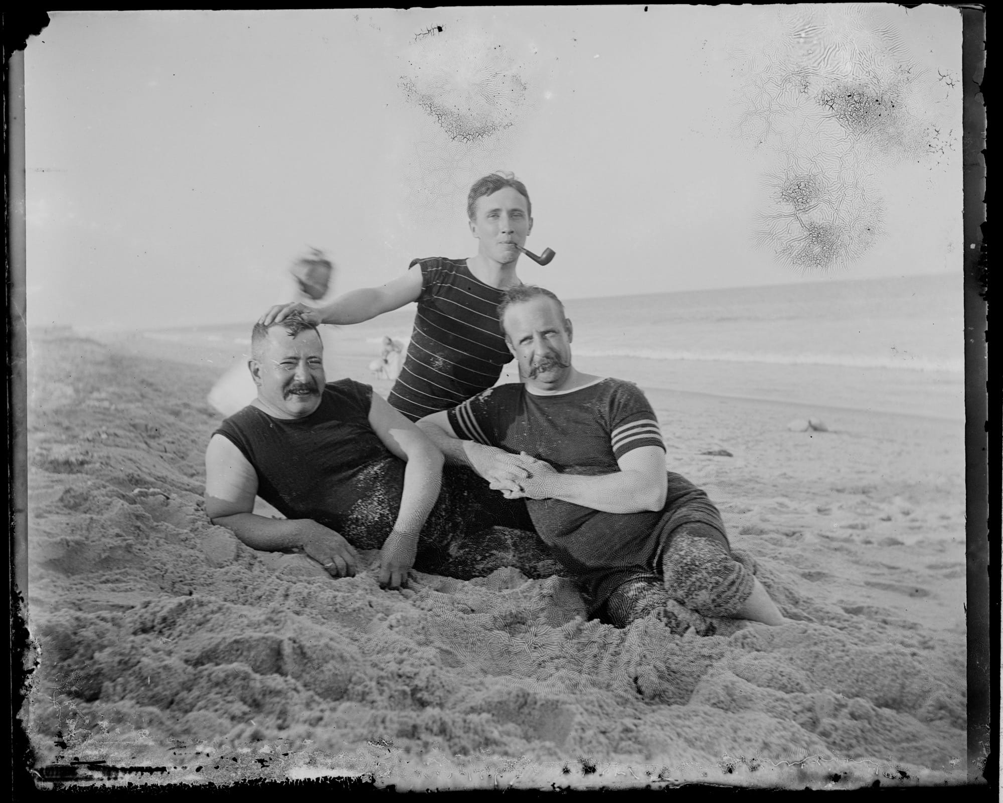 a black-and-white photo from the late 19th century of three men in swimming suits on the New Jersey shore