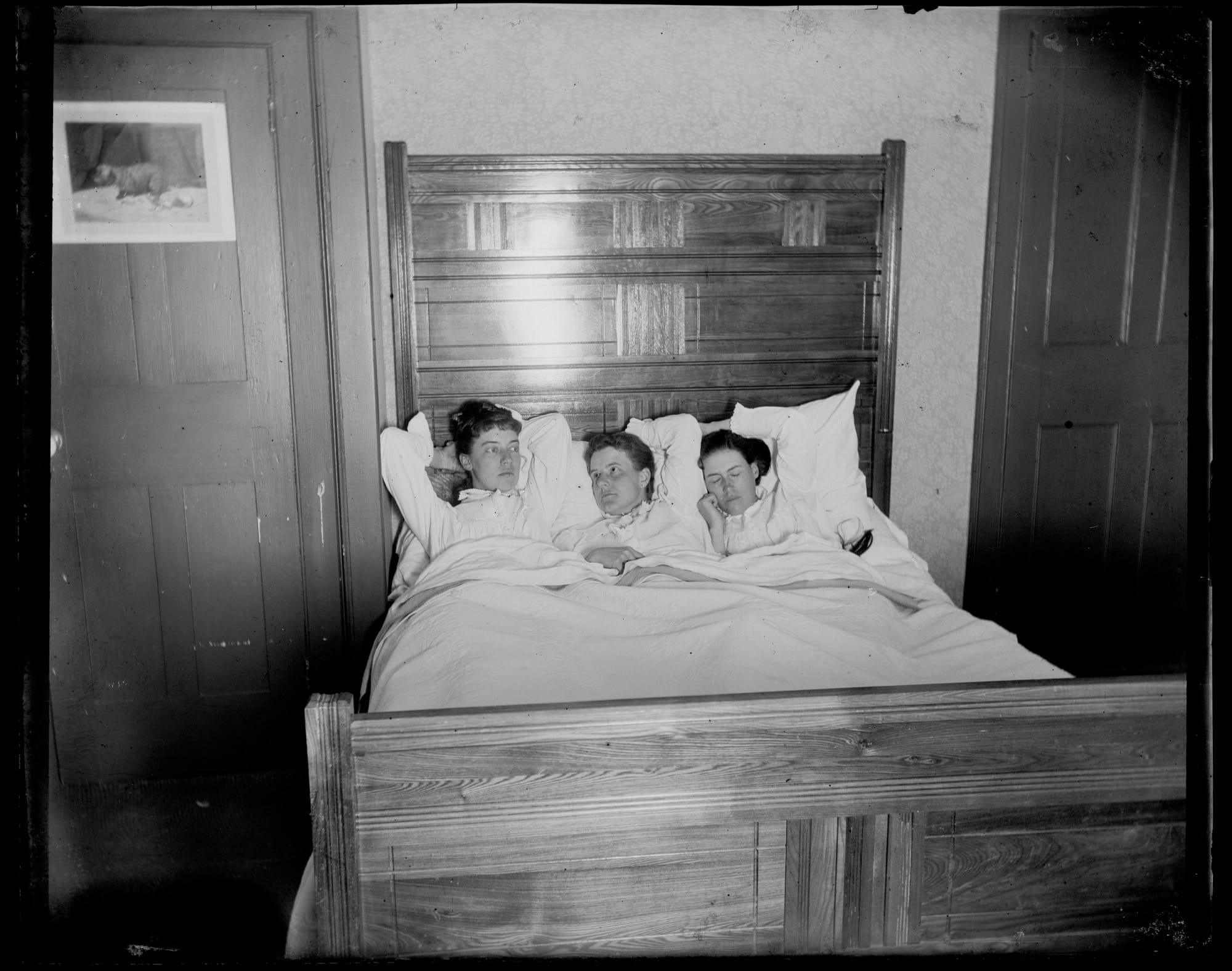 a black-and-white photo from the late 19th century of three women in a bed